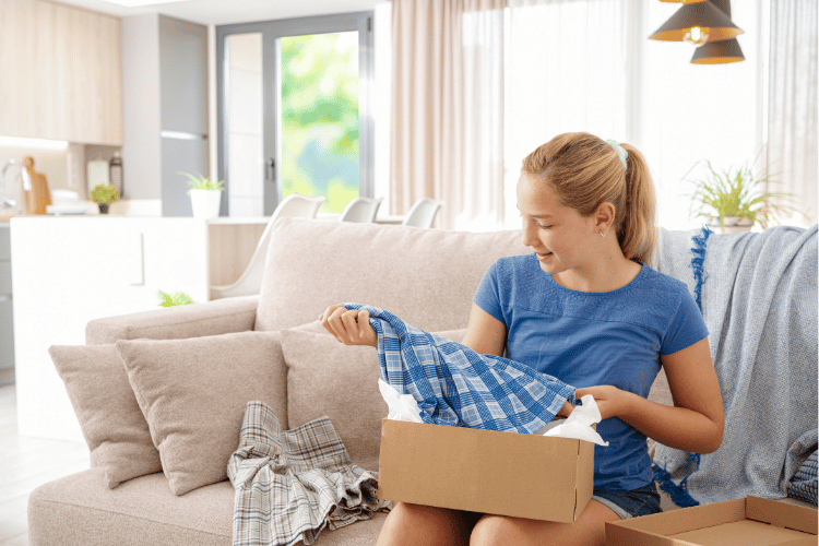Girl opening box with clothes ordered online shopping