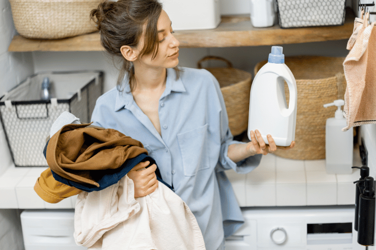 Woman with clothes and detergent in a laundry room